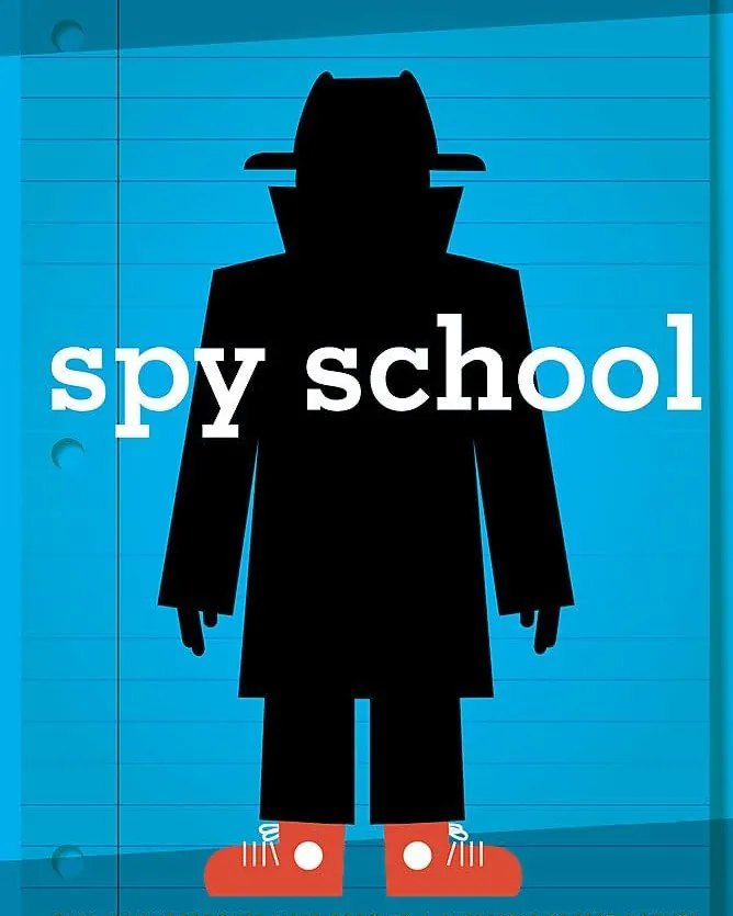 A printed spy-themed activity book on a sleek black table with a laptop and notebook nearby.